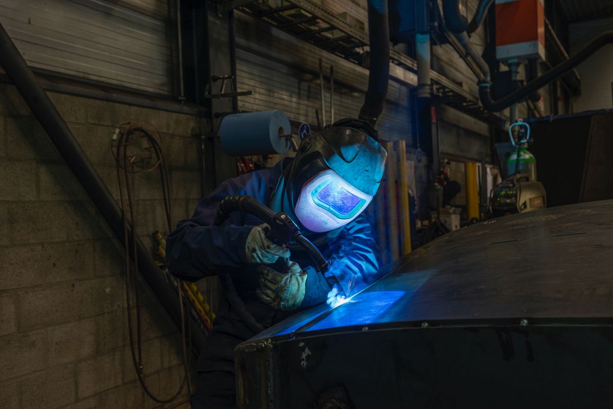 Welder arc-welding a steel workpiece