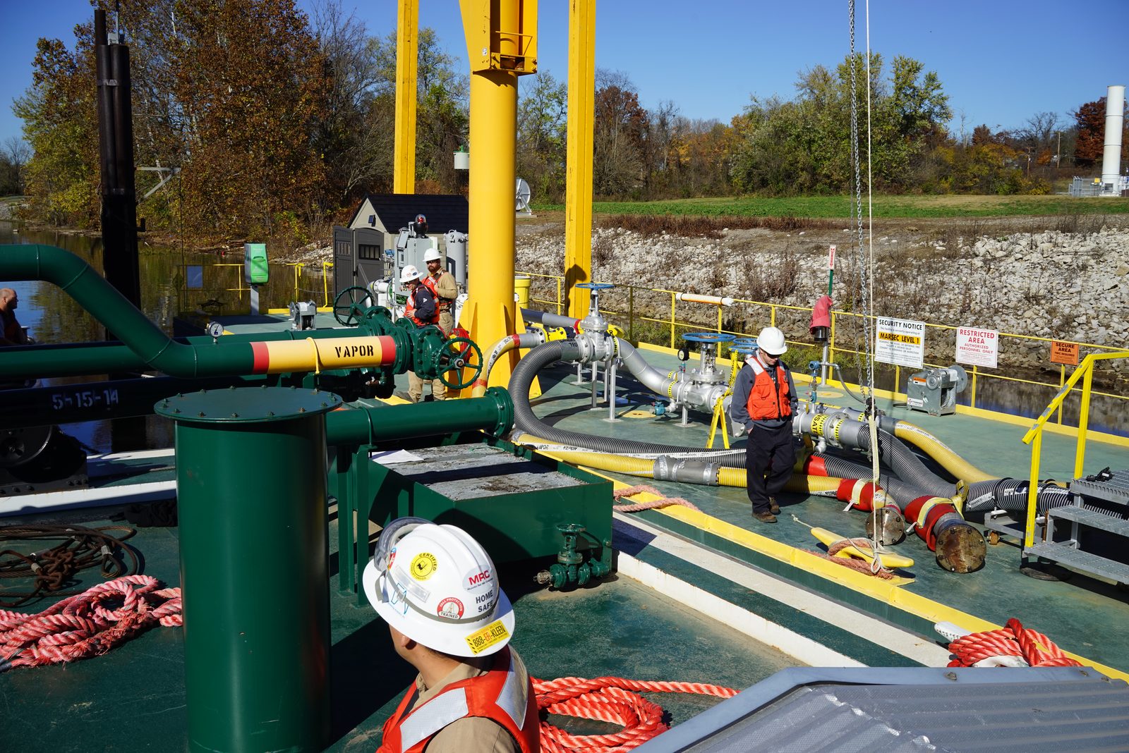 Crew making up transfer hoses on a river barge dock during terminal commissioning
